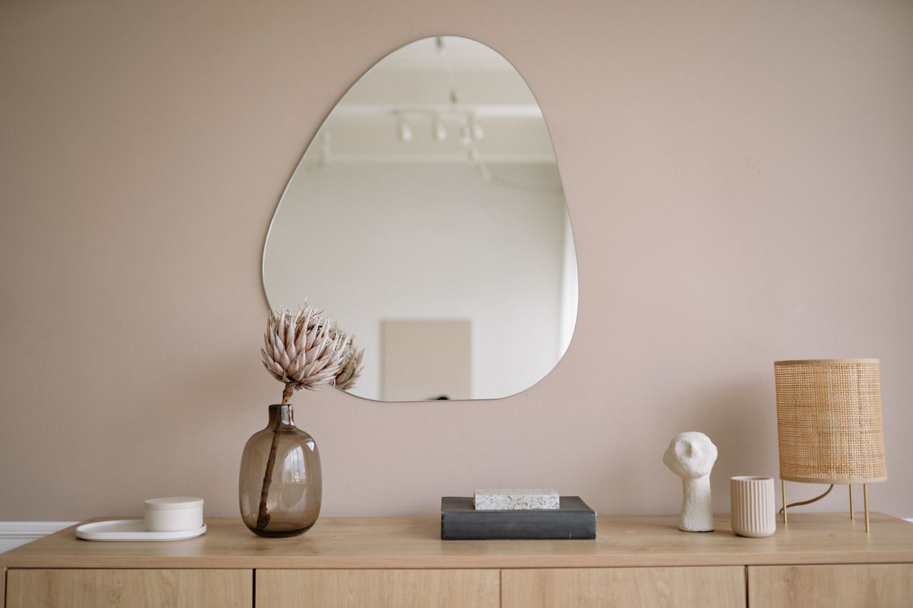 Intérieur minimaliste et élégant avec un miroir, un vase décoratif et une lampe.
